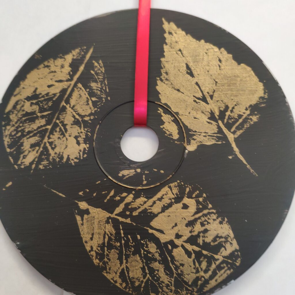 praca plastyczna przedstawiająca 3 złote liście kalkomania na płycie CD