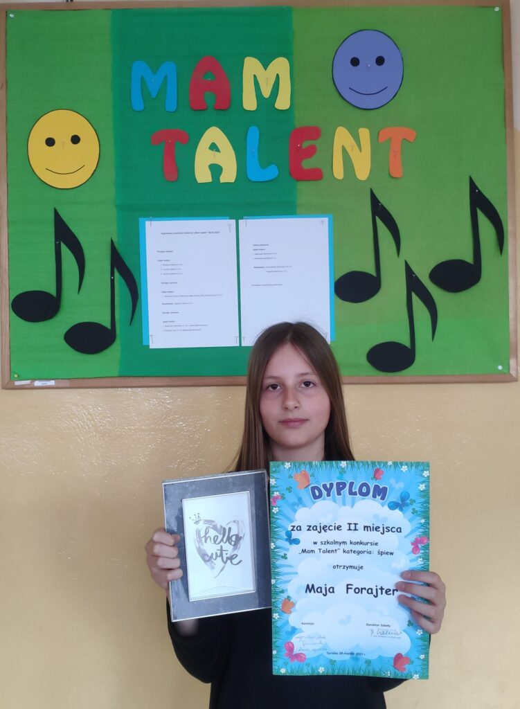 Dziewczyna z klasy piątej trzyma w rękach dyplom za zajęcie II miejsca w konkursie Mam talent.